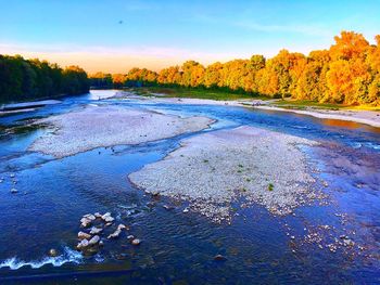 Scenic view of river against sky at sunset