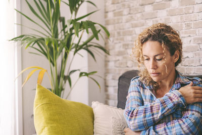 Side view of young woman sitting on sofa at home