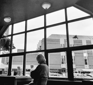 Rear view of man looking through window