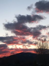 Low angle view of silhouette trees against dramatic sky