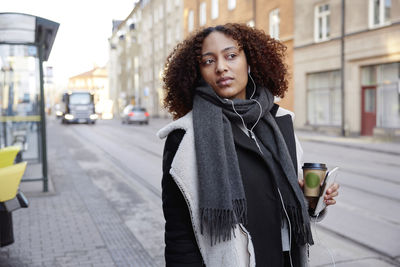 Young woman walking, city street in background