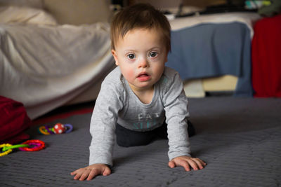 Portrait of cute boy sitting on bed at home