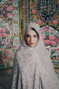 Portrait of young woman standing against wall