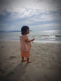 Full length of girl standing at beach against sky