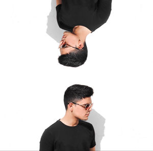 Portrait of young man standing against white background