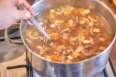 Midsection of person preparing food in cooking pan