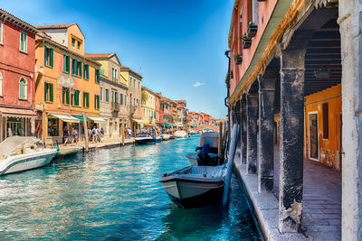 Boats moored in canal amidst buildings in city