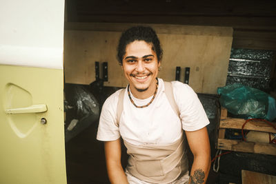 Positive latin american male in casual clothes looking at camera with smile while sitting in modern trailer during road trip