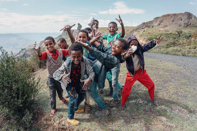 Portrait of young people with arms raised