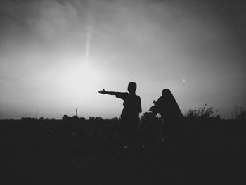 Silhouette boy gesturing while standing by woman