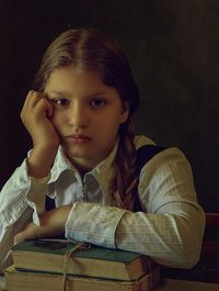 Close-up portrait of girl with books sitting at table