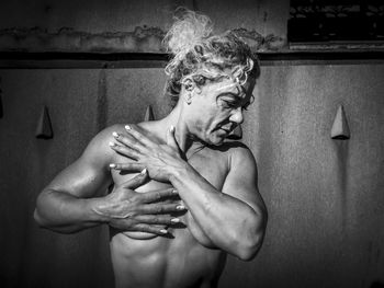 Shirtless of woman standing against wall