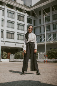 Portrait of woman wearing sunglasses standing against building