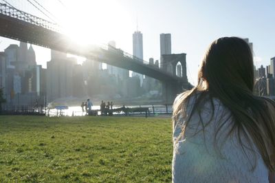 Rear view of woman standing by cityscape against sky