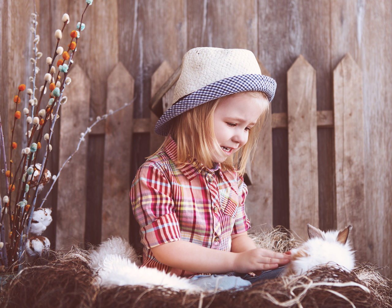 GIRL LOOKING AWAY WHILE SITTING ON WOOD AGAINST WALL