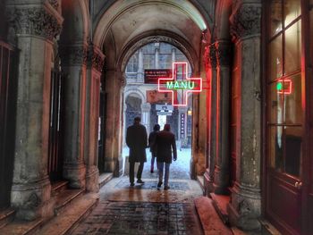 Rear view of people walking on illuminated building