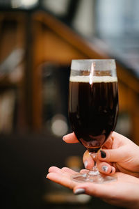 Close-up of hand holding beer glass on table