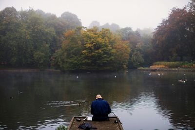 Man sitting on pier over lake