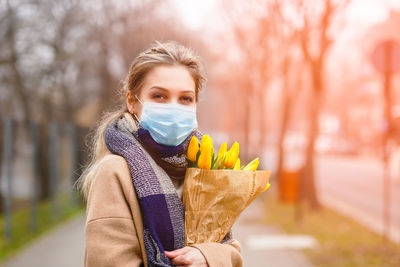 Portrait of woman holding ice cream standing outdoors