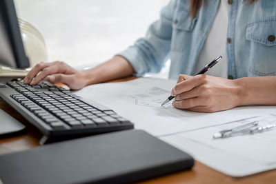 Midsection of woman using laptop on table