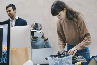 Computer programmer wearing vr glasses while colleagues working in office