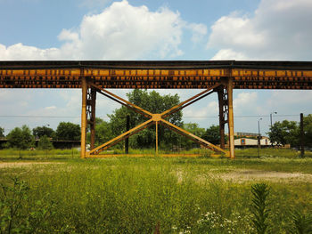 Low angle view of metal structure on grassy field against sky