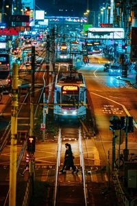 High angle view of people walking on illuminated street at night