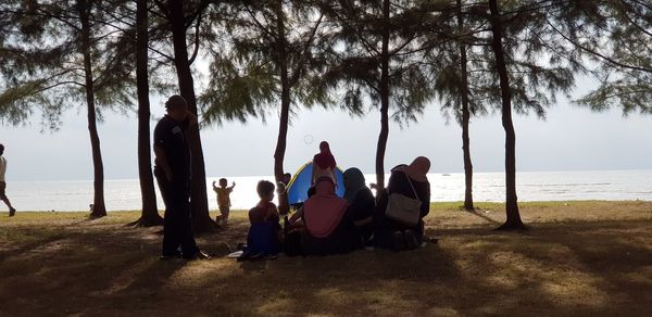 Rear view of people sitting on beach