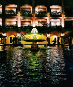 Illuminated swimming pool by lake at night