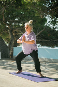 Full length of young woman exercising on field