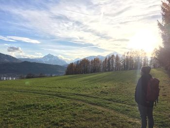 Rear view of man walking on field against sky