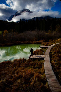 Young man standing by lake during autumn