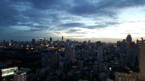Illuminated cityscape against cloudy sky