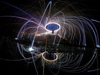 Low angle view of man spinning wire wool at night