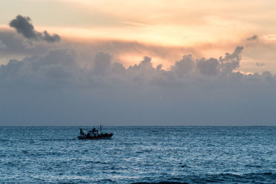 Boat sailing in sea against sky during sunset