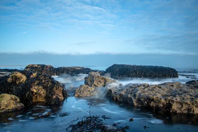 Scenic view of rocky beach against sky