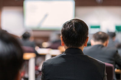 Rear view of businessman sitting in seminar