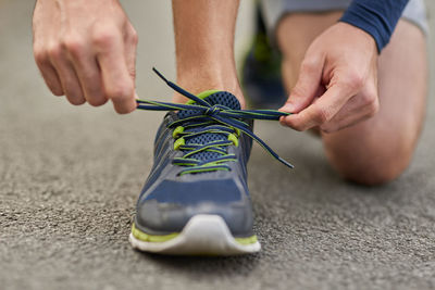 Midsection of man tying shoelace