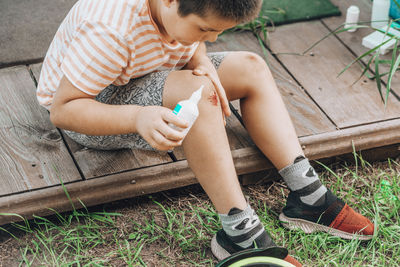 Child's leg injury. child injured his knee, fell off. boy uses an antibacterial agent to treat wound