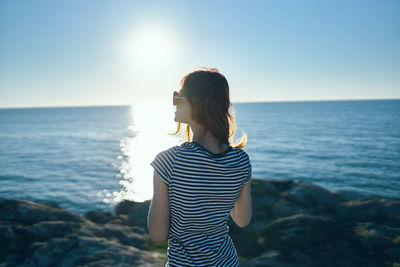 Rear view of young woman looking at sea against sky