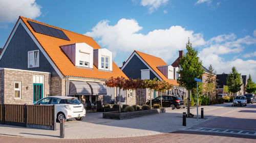 Cars on street by buildings against sky