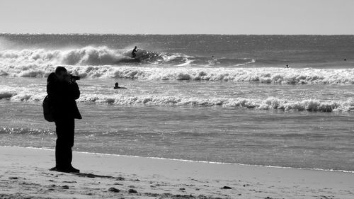 Side view of silhouette man photographing through camera at beach