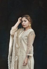 Beautiful young woman standing against wall