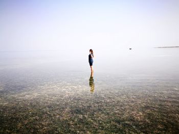 Teenage girl standing in sea against sky