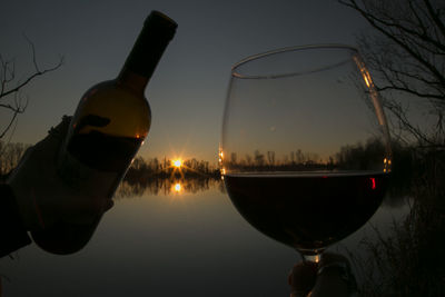 Close-up of beer bottle against sky during sunset