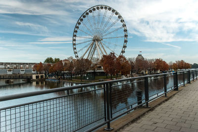 Ferris wheel by river against sky