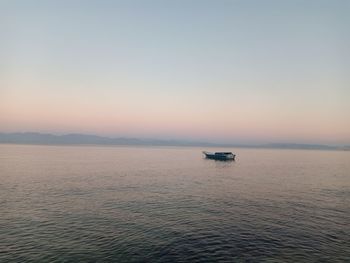 Boat sailing in sea against sky during sunset