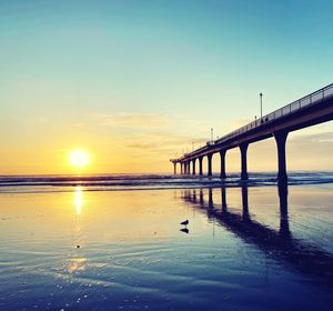 Bridge over sea against sky during sunset