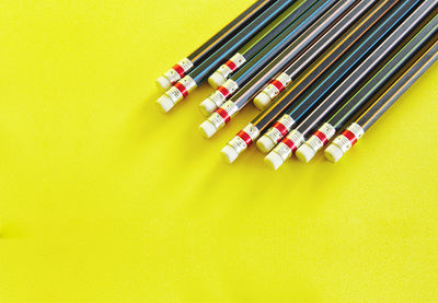 High angle view of colored pencils on yellow background