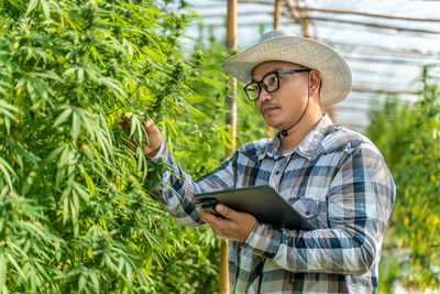 Young woman wearing hat standing against plants